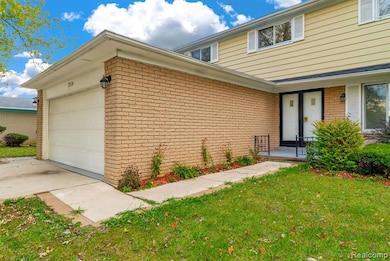View of front facade with brick siding, a front lawn, concrete driveway, and a garage