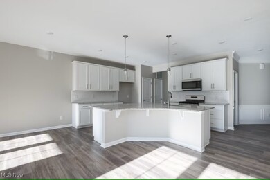 Kitchen with tasteful backsplash, light stone countertops, white cabinets, a breakfast bar area, and decorative light fixtures