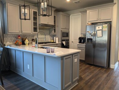 Kitchen featuring island, stainless steel appliances, decorative backsplash, and pendant lighting