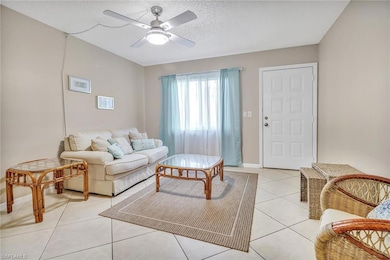 Living room with a textured ceiling, ceiling fan, and light tile patterned floors