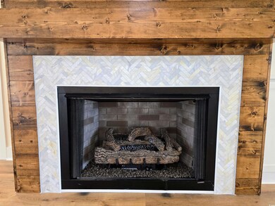 Wood stained shiplap, chunky mantel, marble hexagon surround, gas log fireplace.