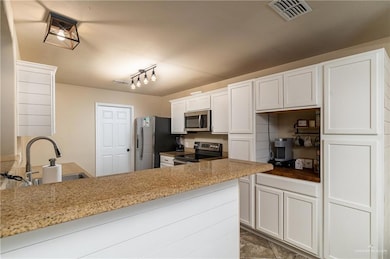 Kitchen featuring appliances with stainless steel finishes, white cabinetry, and a peninsula