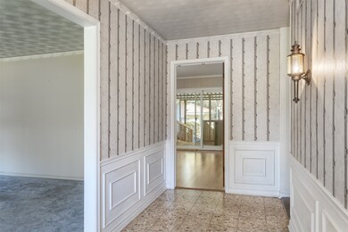 Hallway featuring wallpapered walls, wainscoting, and ornamental molding