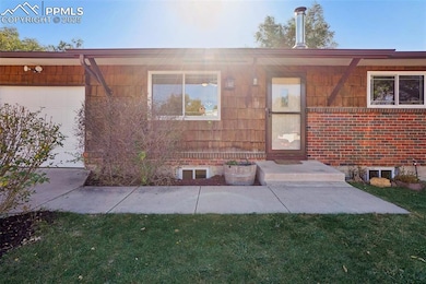 Front view of house with a yard, a garage, and brick siding