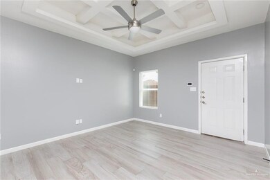 Empty room with coffered ceiling, ceiling fan, light wood-type flooring, and beamed ceiling