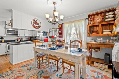 Dining space with light wood finished floors, a chandelier, a textured ceiling, and crown molding