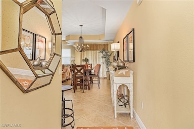 Hall featuring light tile patterned floors, a notable chandelier, and baseboards