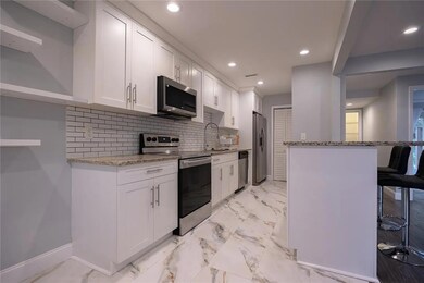 Kitchen with light stone counters, appliances with stainless steel finishes, white cabinetry, tasteful backsplash, and recessed lighting
