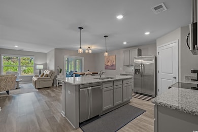 Kitchen featuring gray cabinetry, light stone countertops, light wood-style flooring, appliances with stainless steel finishes, and recessed lighting