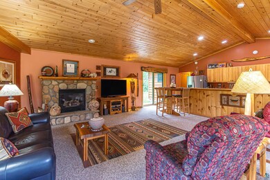 Living room featuring a stone fireplace, ceiling f