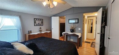 Bedroom featuring lofted ceiling, light hardwood / wood-style floors, a textured ceiling, and ceiling fan