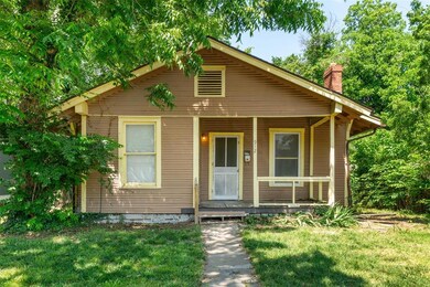 Bungalow-style home with covered porch, a chimney, and a front lawn