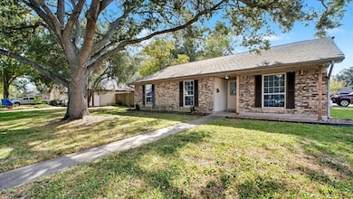 Another angle of the front exterior showcasing the spacious front yard and charming brick façade. The tree canopy adds natural beauty and creates a peaceful, inviting entrance.