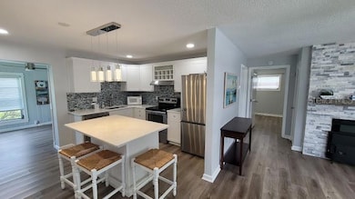 The center of the home houses a beautiful kitchen with an island. The hallway on the right leads you to the Primary Suite.