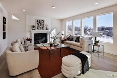 Living area featuring a glass covered fireplace, recessed lighting, and light wood-style flooring