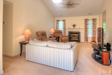 Fabulous family room boasting a gas fireplace, ceiling fan, plush carpet, and vaulted ceiling!
