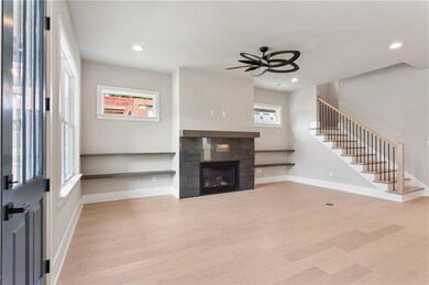Unfurnished living room with a ceiling fan, light wood finished floors, stairs, recessed lighting, and a tiled fireplace