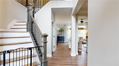 Entryway with ceiling fan, wood finished floors, stairway, ornamental molding, and baseboards