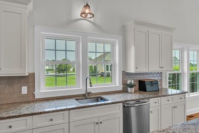 Windows over the kitchen sink overlooks open common area with a lush green lawn.