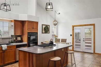 Kitchen with a sink, stainless steel appliances, high vaulted ceiling, a kitchen breakfast bar, and brown cabinetry