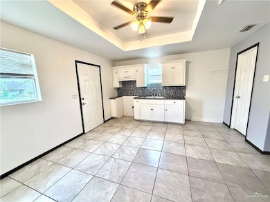 Kitchen featuring a raised ceiling, ceiling fan, backsplash, and healthy amount of natural light
