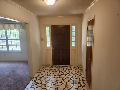 Foyer with ornamental molding, light carpet, and a