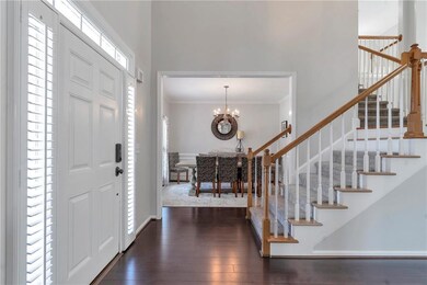 Entrance foyer with stairway, a chandelier, hardwood / wood-style flooring, ornamental molding, and a high ceiling