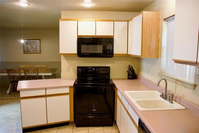 Kitchen featuring black appliances, light tile floors, white cabinets, sink, and kitchen peninsula