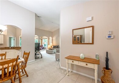 Hallway with arched walkways, lofted ceiling, and light colored carpet