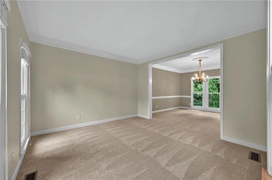 Dining room/Living room with light colored carpet, a chandelier, ornamental molding, and baseboards