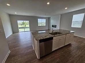 Kitchen with a center island with sink, open floor plan, recessed lighting, stainless steel dishwasher, and white cabinetry