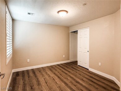 Bedroom with dark wood-type flooring, multiple windows, a closet, and a textured ceiling
