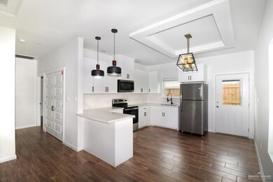 Kitchen with white cabinets, appliances with stainless steel finishes, hanging light fixtures, and sink