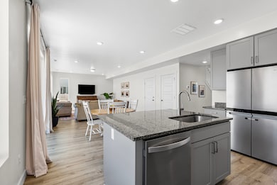 Kitchen featuring gray cabinetry, dark stone counters, appliances with stainless steel finishes, recessed lighting, and open floor plan