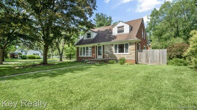 Spacious, tree-lined front yard with lush grass and classic brick exterior