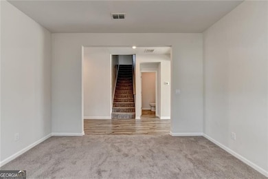 Empty room with baseboards, visible vents, carpet,