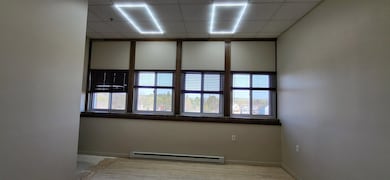 Spare room with a baseboard heating unit, a paneled ceiling, healthy amount of natural light, and light wood-style floors