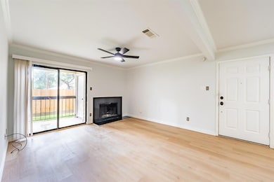 Unfurnished living room featuring crown molding, light wood-style floors, a fireplace, a ceiling fan, and beamed ceiling