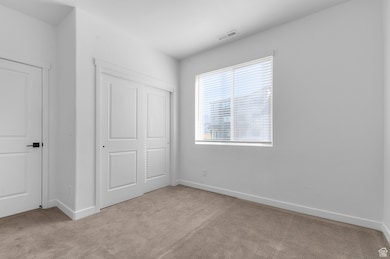 Unfurnished bedroom featuring light colored carpet and a closet
