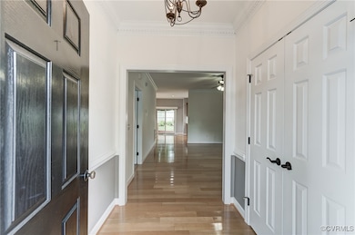 Hallway with crown molding, light wood-style floor