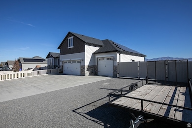 View of home's exterior with a gate, solar panels, driveway, stone siding, and an attached garage