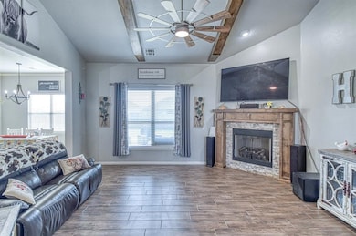Living room with wood tiled floors, a ceiling fan, a fireplace, and a chandelier