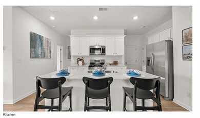 Kitchen featuring stainless steel appliances, white cabinets, a breakfast bar, recessed lighting, and a center island with sink