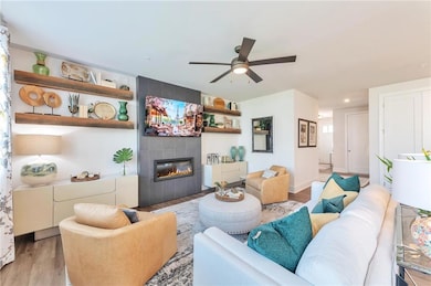 The open concept living room features large windows, luxury plank flooring, and soaring 9-foot ceilings that create a warm and inviting atmosphere.