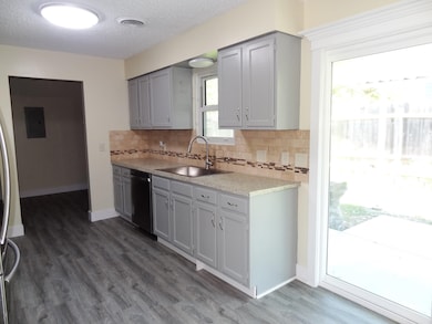 Kitchen featuring gray cabinets, dark wood-style floors, a textured ceiling, decorative backsplash, and appliances with stainless steel finishes