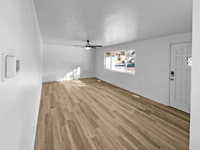 Unfurnished living room featuring light wood-style floors, ceiling fan, and a textured ceiling
