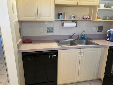 Kitchen featuring light tile patterned flooring, black appliances, tasteful backsplash, and light countertops