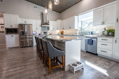 Kitchen with white cabinetry, tasteful backsplash, stainless steel appliances, wooden ceiling, and light stone counters
