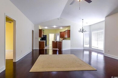 Kitchen featuring vaulted ceiling, a chandelier, freestanding refrigerator, open floor plan, and dark wood-type flooring