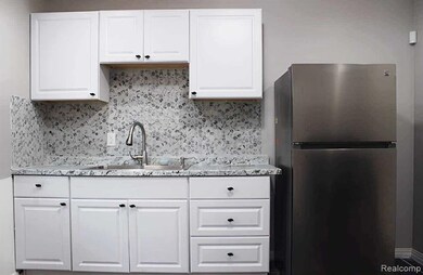 Kitchen with freestanding refrigerator, white cabinetry, and tasteful backsplash